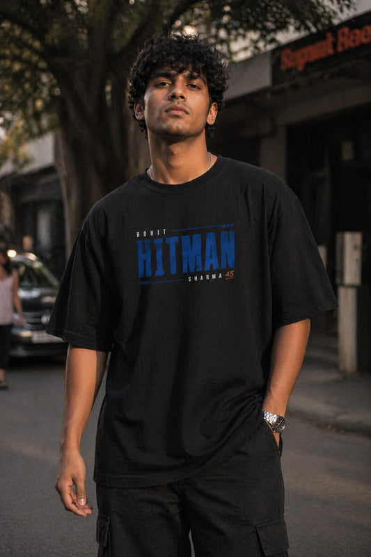 Man wearing a black t-shirt with blue text standing on a street.