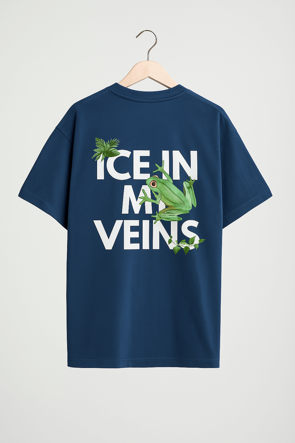 Navy blue oversized SoulSet T-shirt hanging on wooden hanger with “ICE IN MY VEINS” text and frog with tropical leaf graphics.