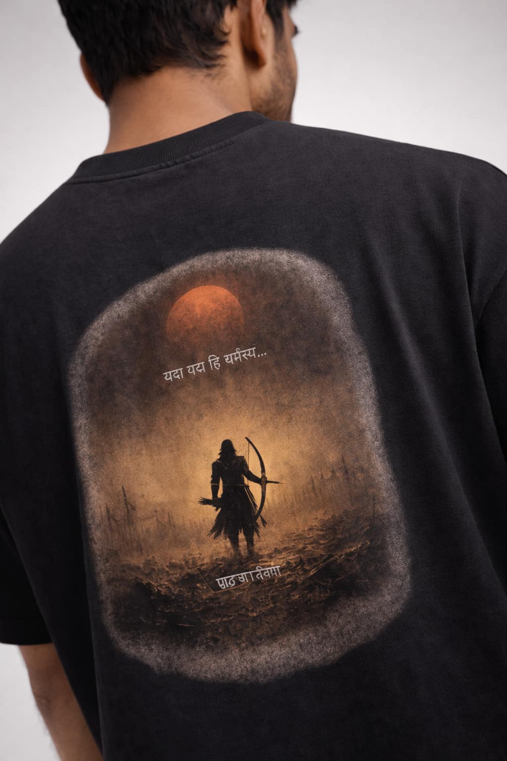 Black t-shirt with a warrior silhouette and sunset design on the back, worn by a person.