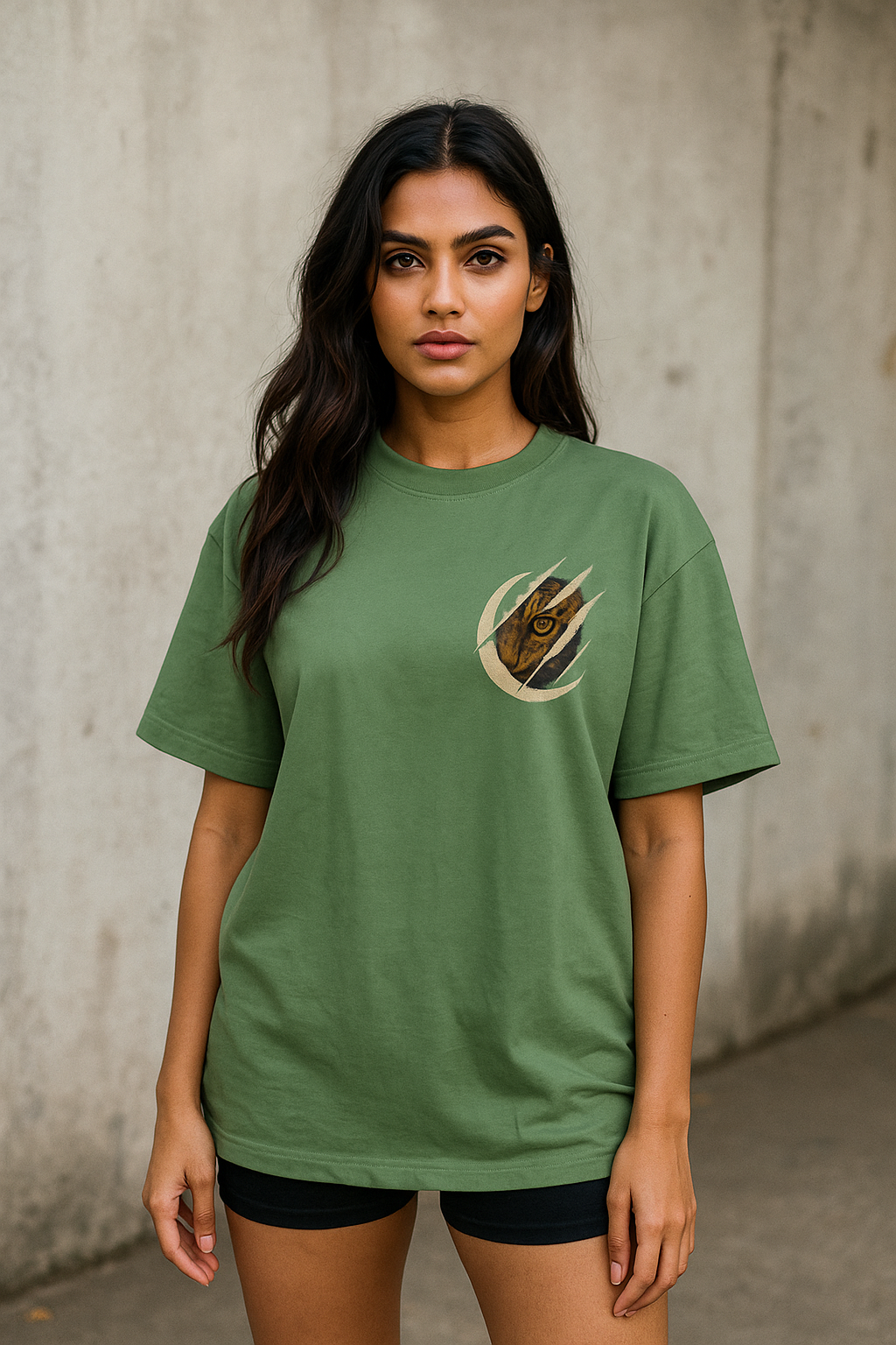 Woman wearing a green t-shirt with a logo against a concrete wall.