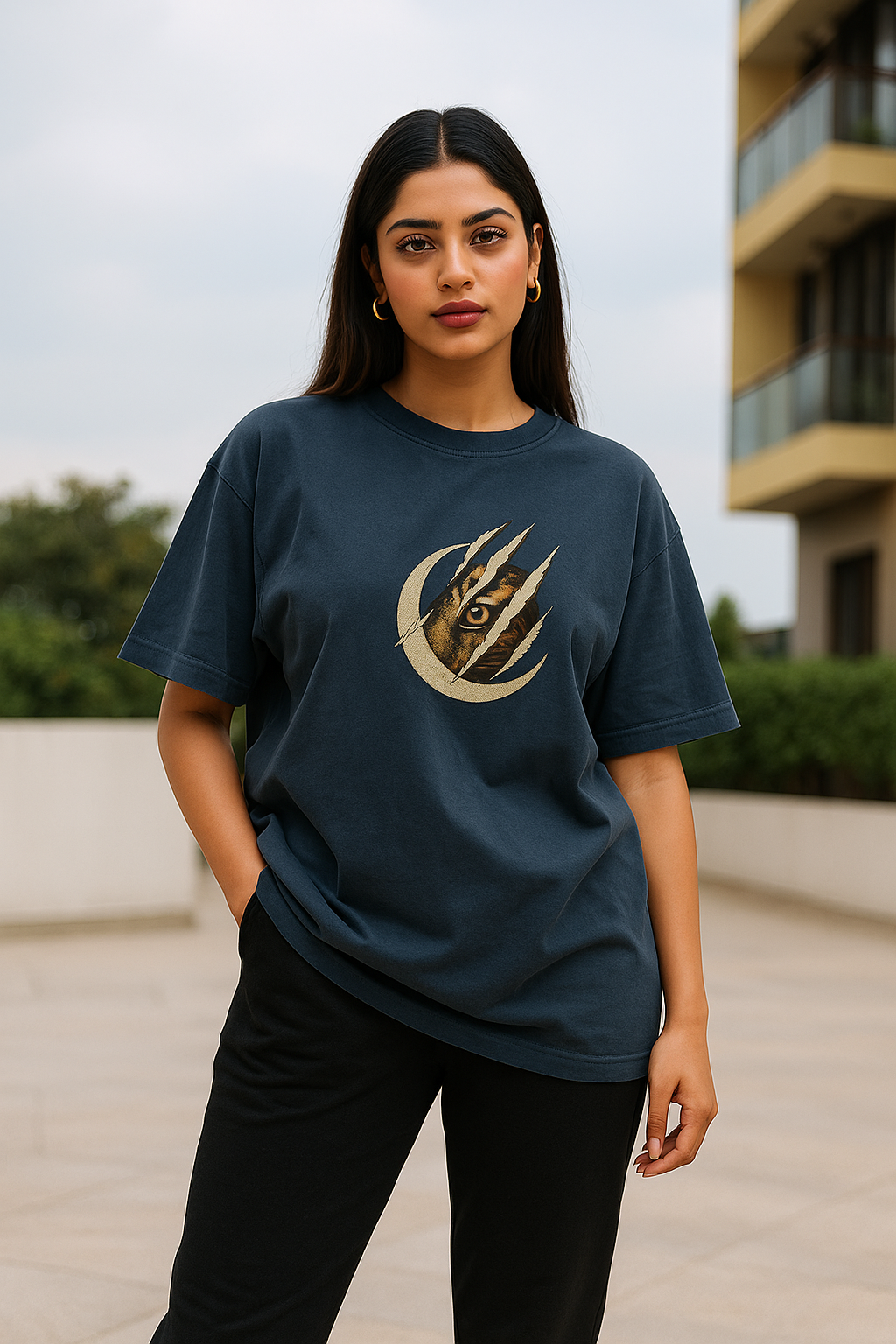 Woman wearing a dark blue t-shirt with a graphic design outdoors.