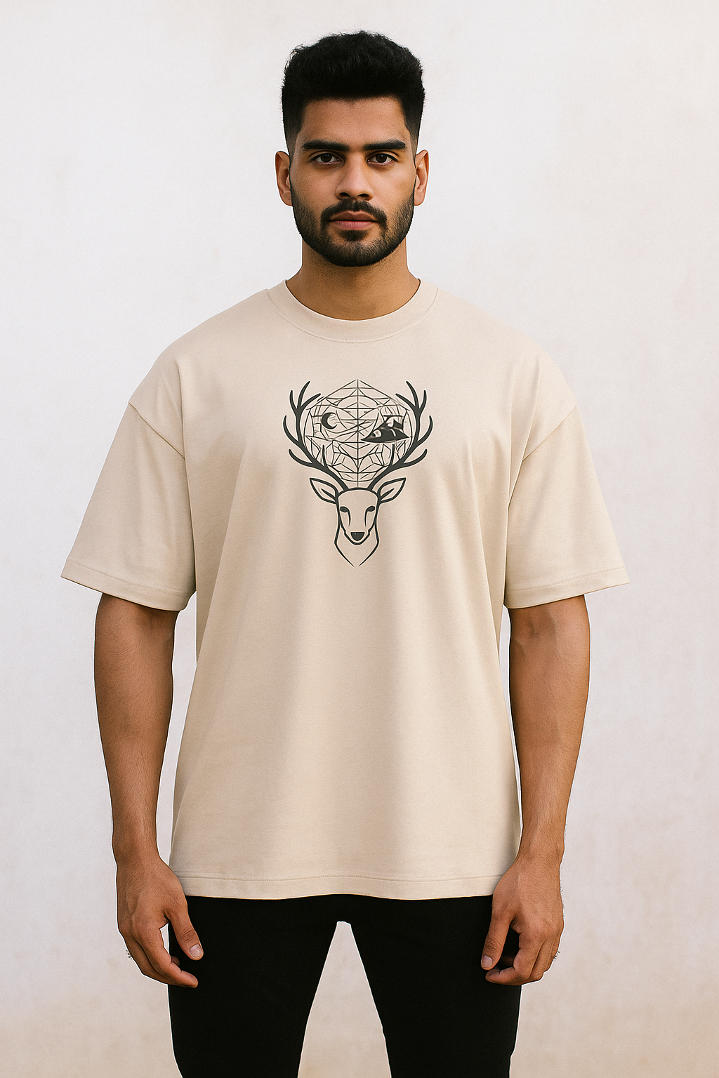 Oversized unisex t-shirt featuring a minimalist deer head with sacred geometry antlers, moon and mountain silhouettes, and a full-back design of a stag on a cliff with a glowing moon and forest tree hem โ premium 240 GSM cotton, made in India.
