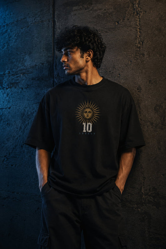 Person wearing a black t-shirt with a sun design against a dark textured wall