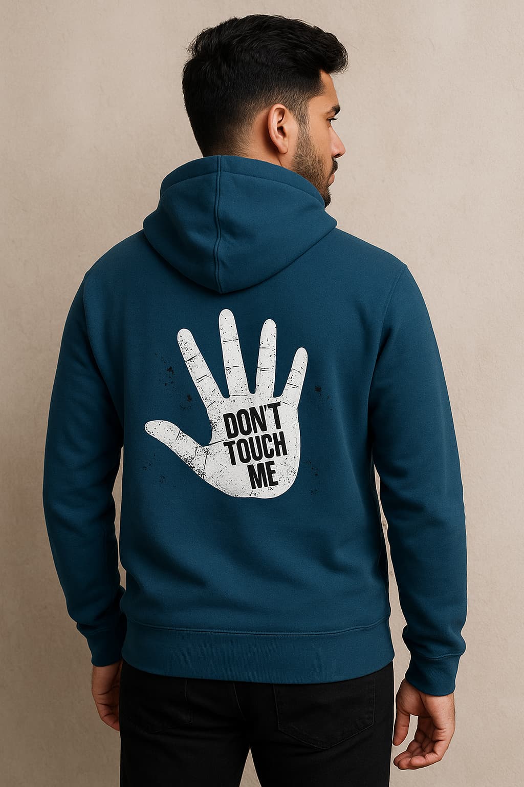 Man wearing a teal hoodie with 'Don't Touch Me' design on the back against a beige background
