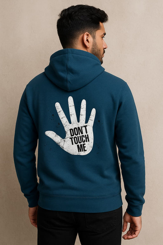 Man wearing a teal hoodie with 'Don't Touch Me' design on the back against a beige background