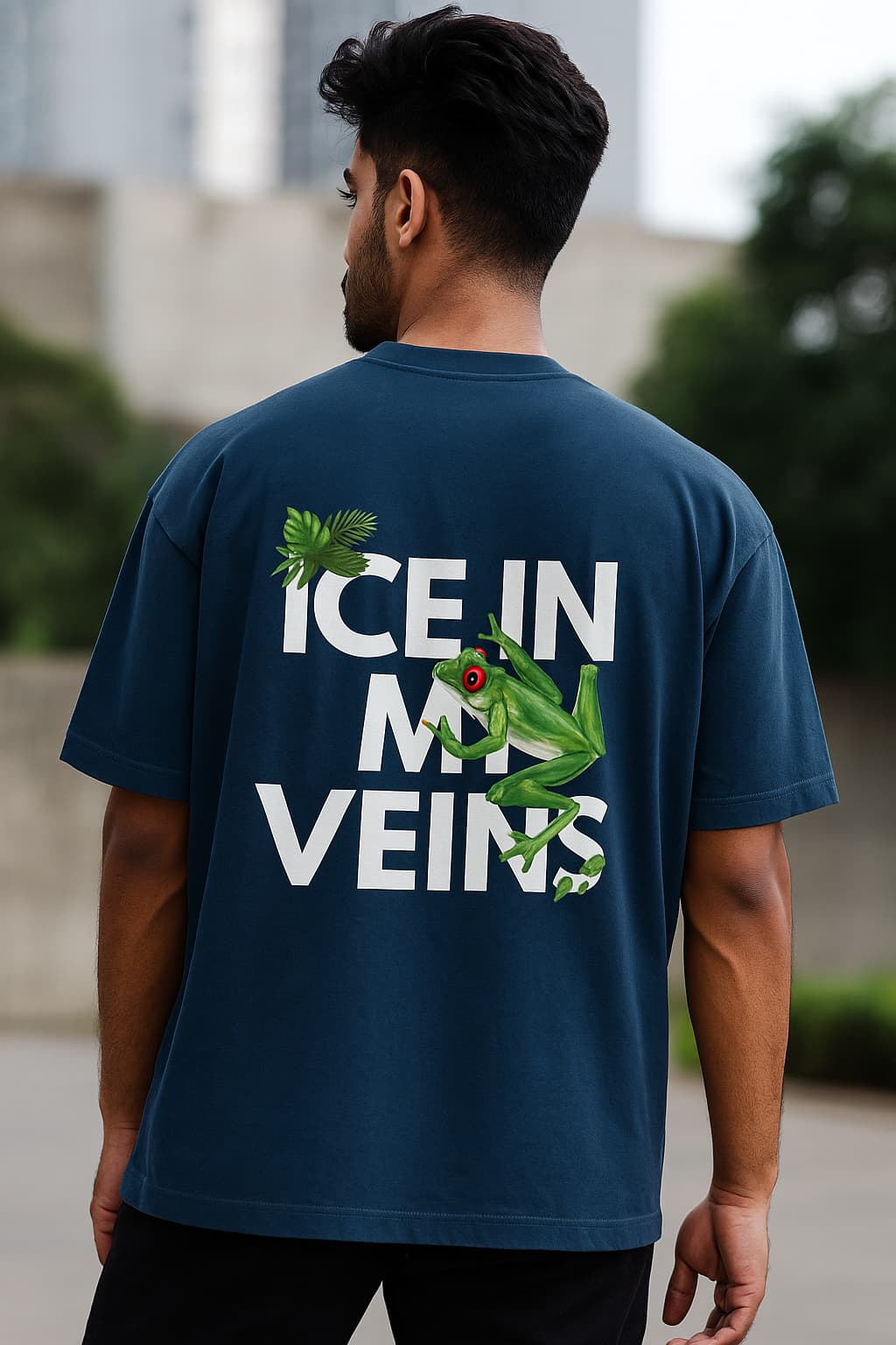 Man wearing a blue t-shirt with a graphic and text on the back, standing outdoors.