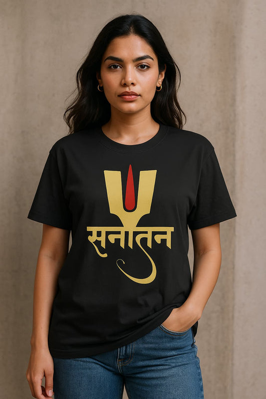 A stylish young Indian woman wearing a black oversized T-shirt with a golden-yellow and red 'Sanatan' design in Devanagari script, standing against a neutral background with one hand in her pocket