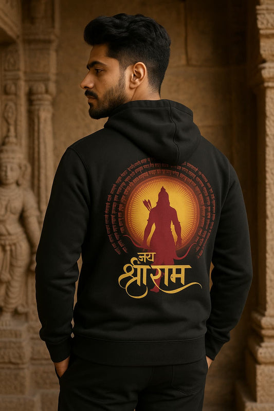 Person wearing a black hoodie with a red and yellow design on the back, standing in front of a stone wall.