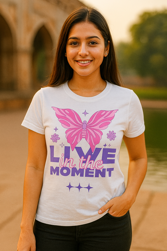 Woman wearing a white t-shirt with a pink butterfly and motivational text outdoors.