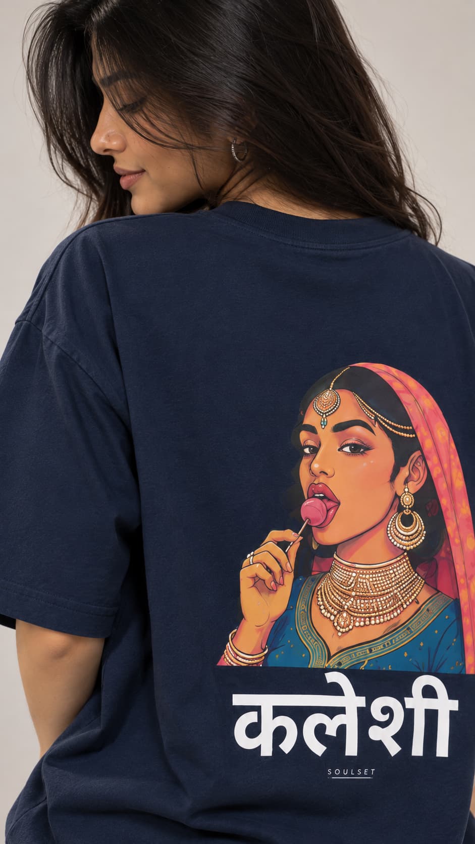 A woman wearing a navy blue t-shirt from the back, featuring a large graphic print of a woman in traditional Indian attire with a pink headscarf and the name 'Kaleesh' in Devanagari script.