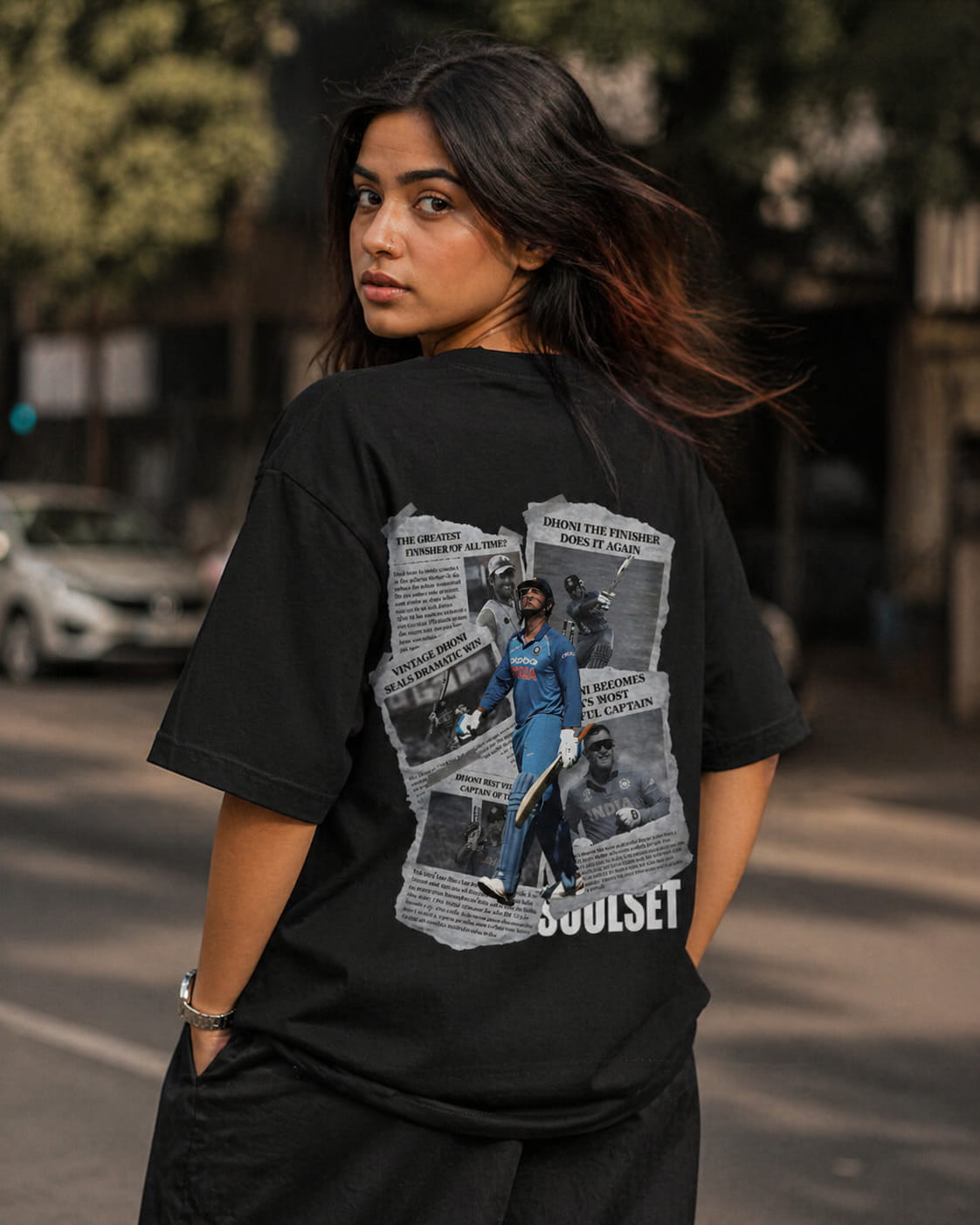 Person wearing a black t-shirt with a graphic design on the back, standing outdoors.