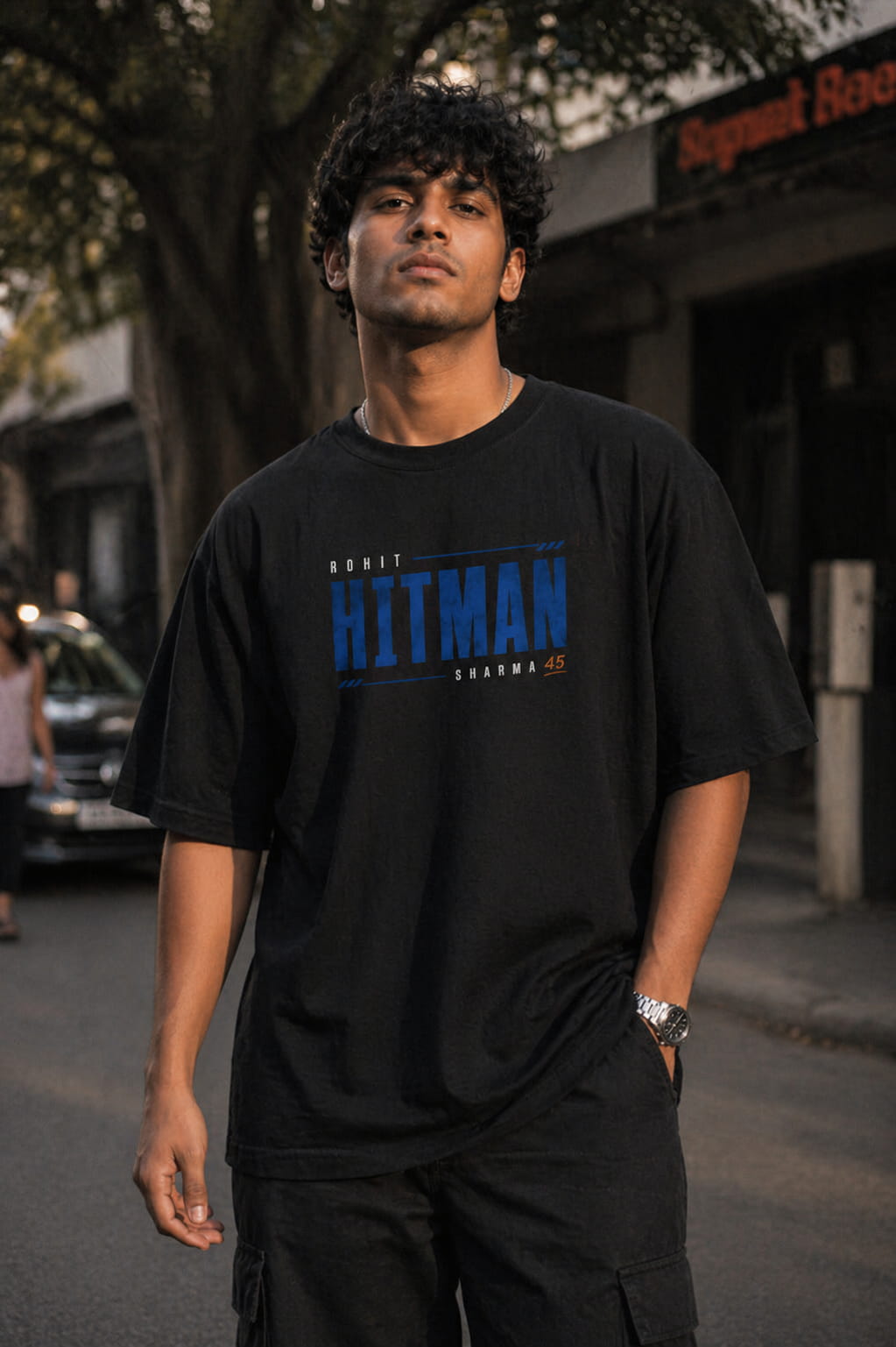 Man wearing a black t-shirt with blue text standing on a street.