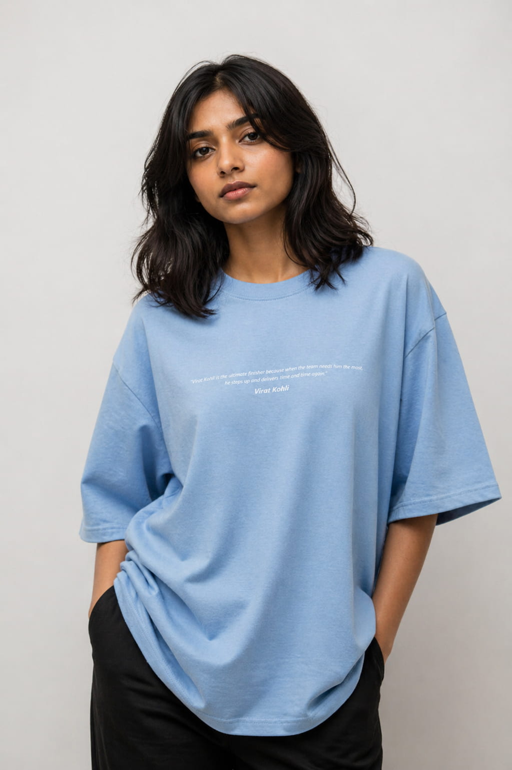 Woman wearing a light blue t-shirt with text on a plain background