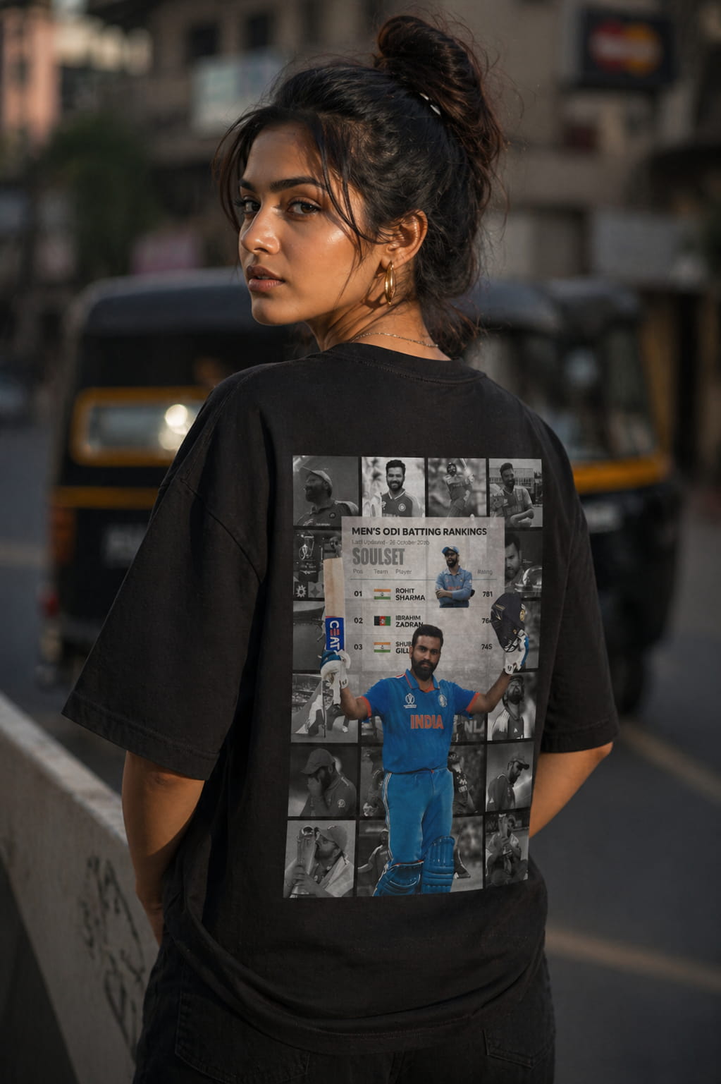 Woman wearing a black t-shirt with a graphic design on the back, standing in an urban setting.