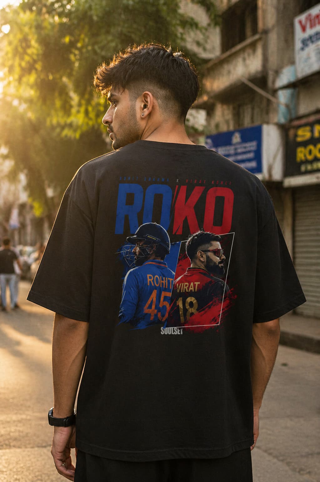 Man wearing a black t-shirt with colorful graphics and text on a street.