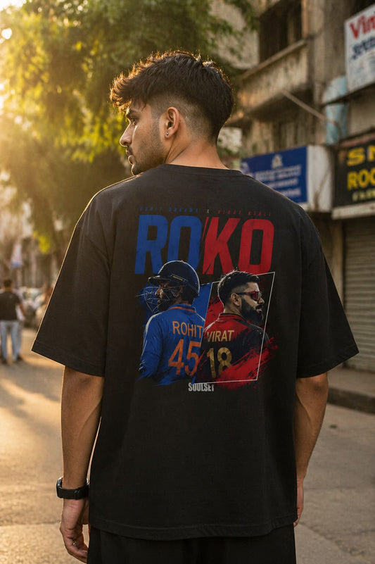 Man wearing a black t-shirt with colorful graphics and text on a street.