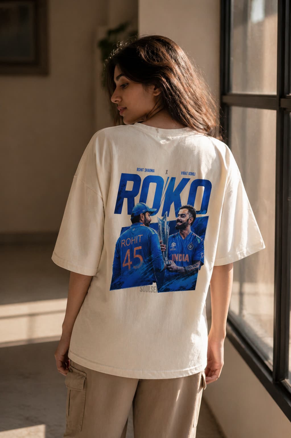 Person wearing a white t-shirt with a graphic and text, standing indoors.