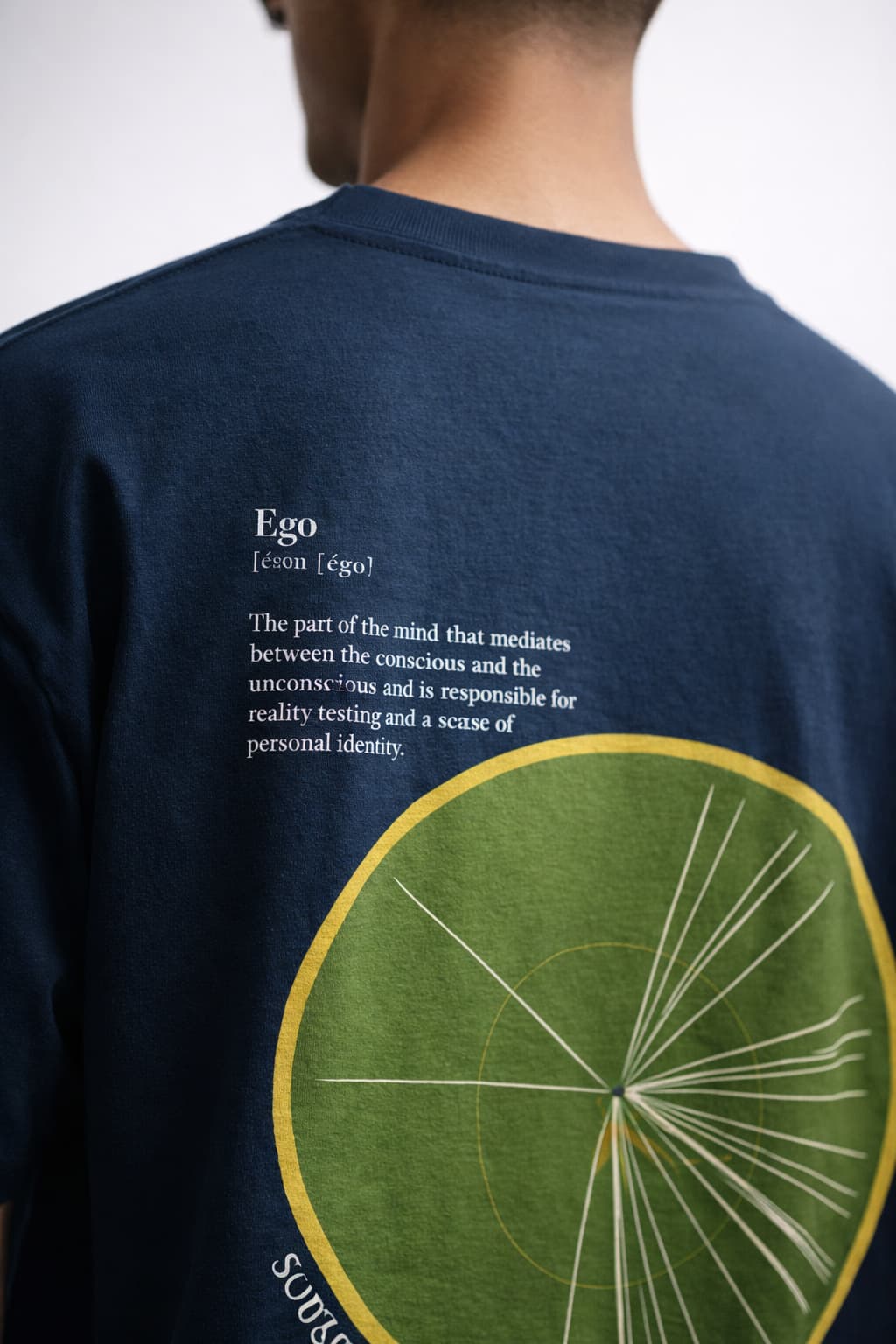 Navy blue t-shirt with green circular design and text on the back, worn by a person.