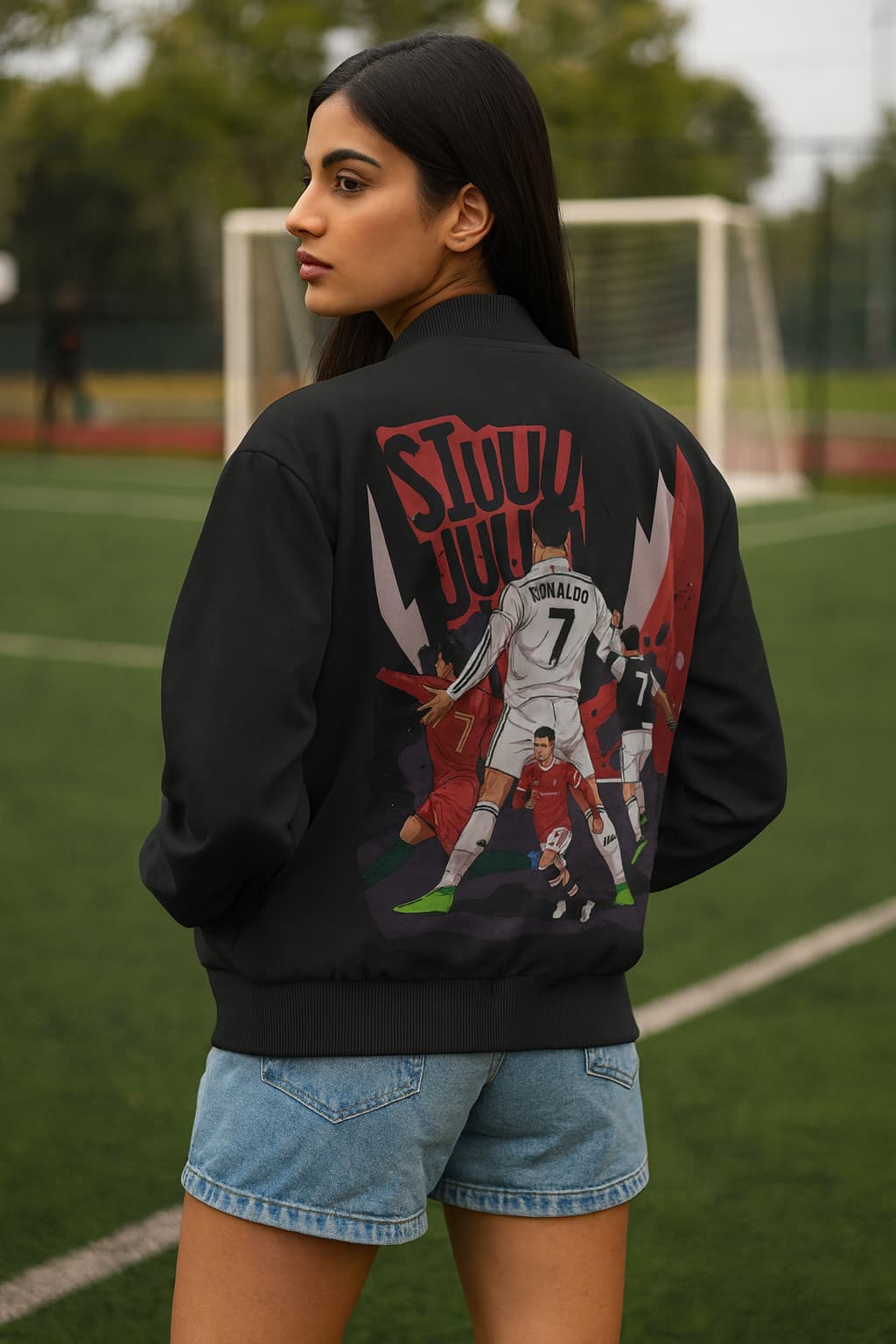 Person wearing a black jacket with graphic designs on a sports field