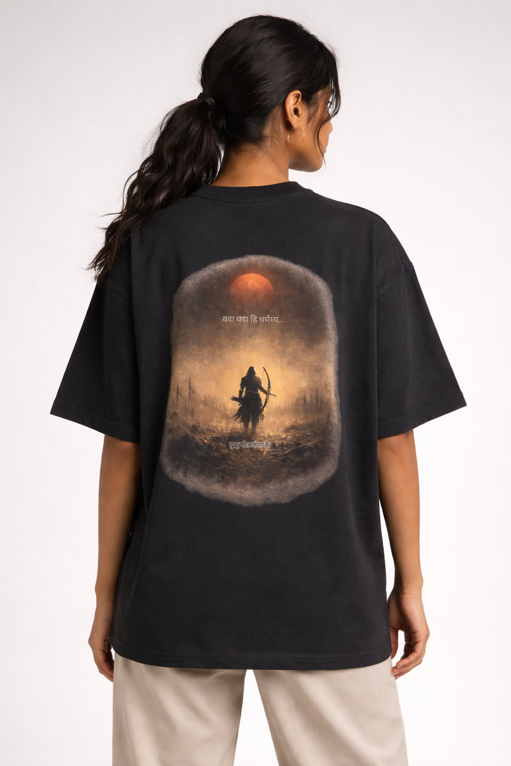 Person wearing a black t-shirt with a graphic design on the back, featuring a warrior and sunset.