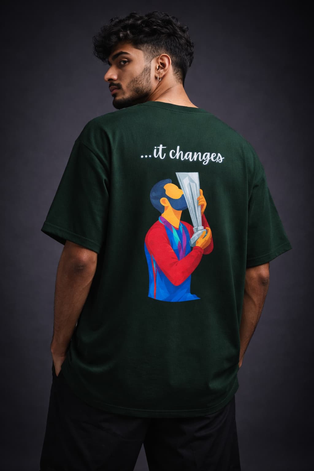 Person wearing a green t-shirt with a graphic and text on the back against a dark background