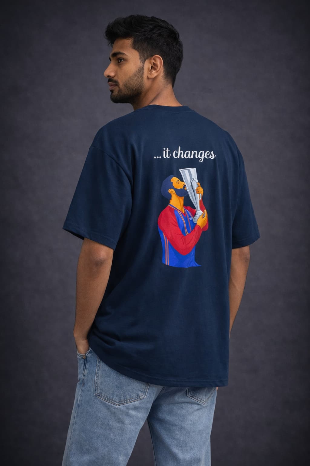 Person wearing a navy blue t-shirt with a graphic design on the back against a dark background