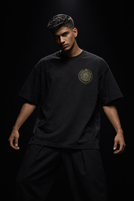 Man wearing a black t-shirt with a logo on a dark background