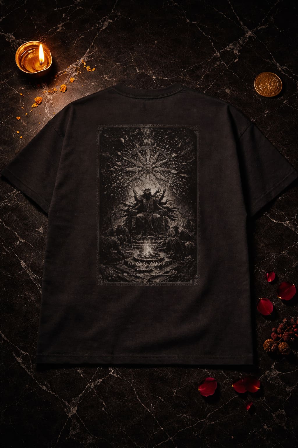 Black t-shirt with a dark graphic design on a textured surface with a candle and coins.