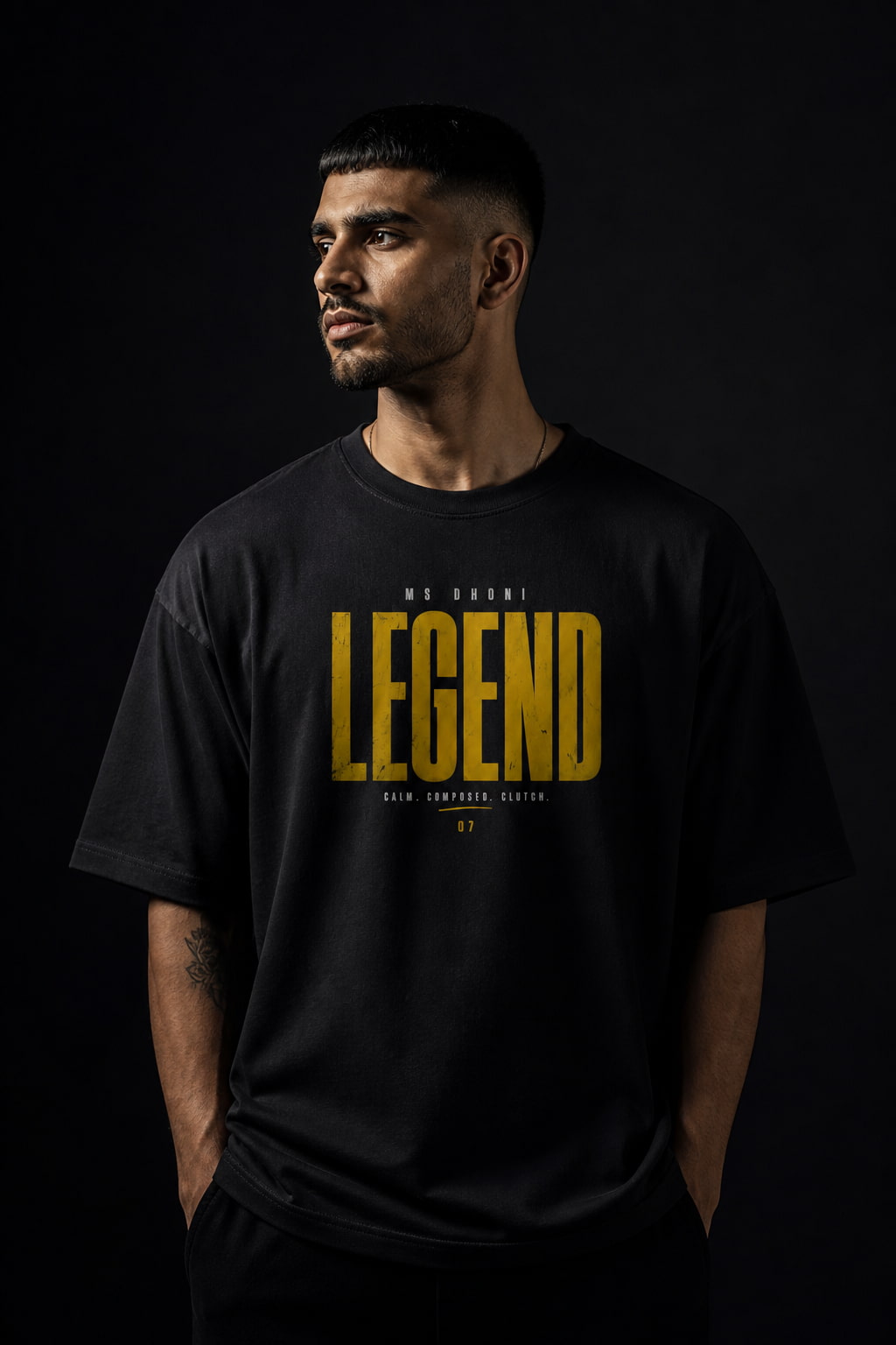 Man wearing a black t-shirt with 'LEGEND'DHONI  printed in yellow on a dark background