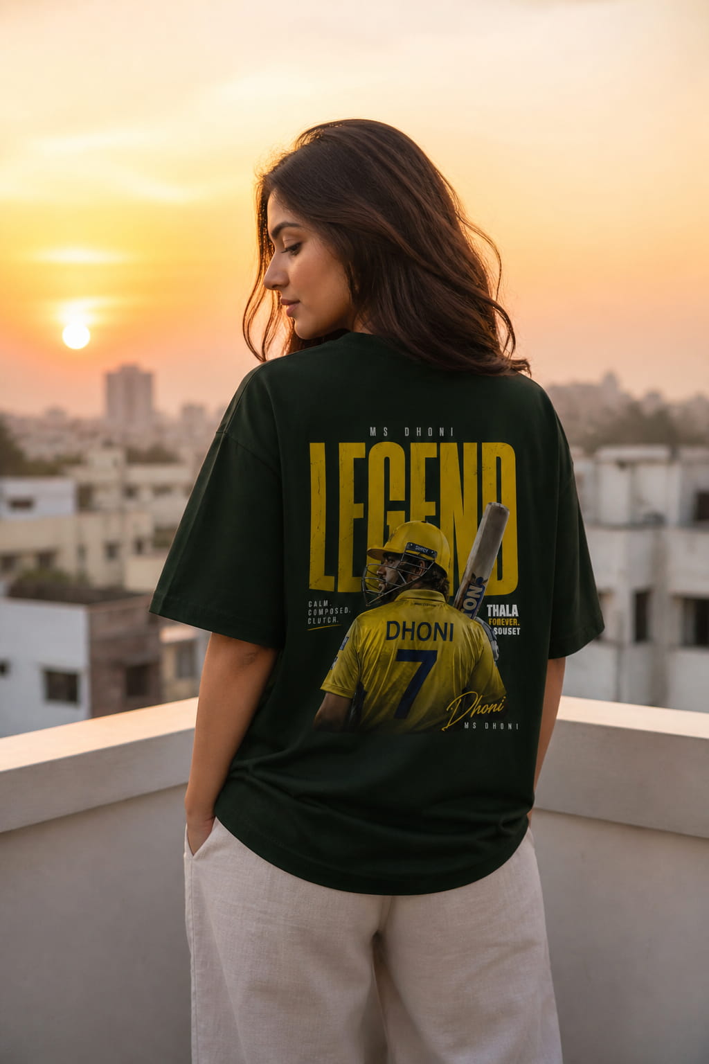 Person wearing a t-shirt with a graphic and text, standing on a rooftop with a cityscape and sunset in the background.