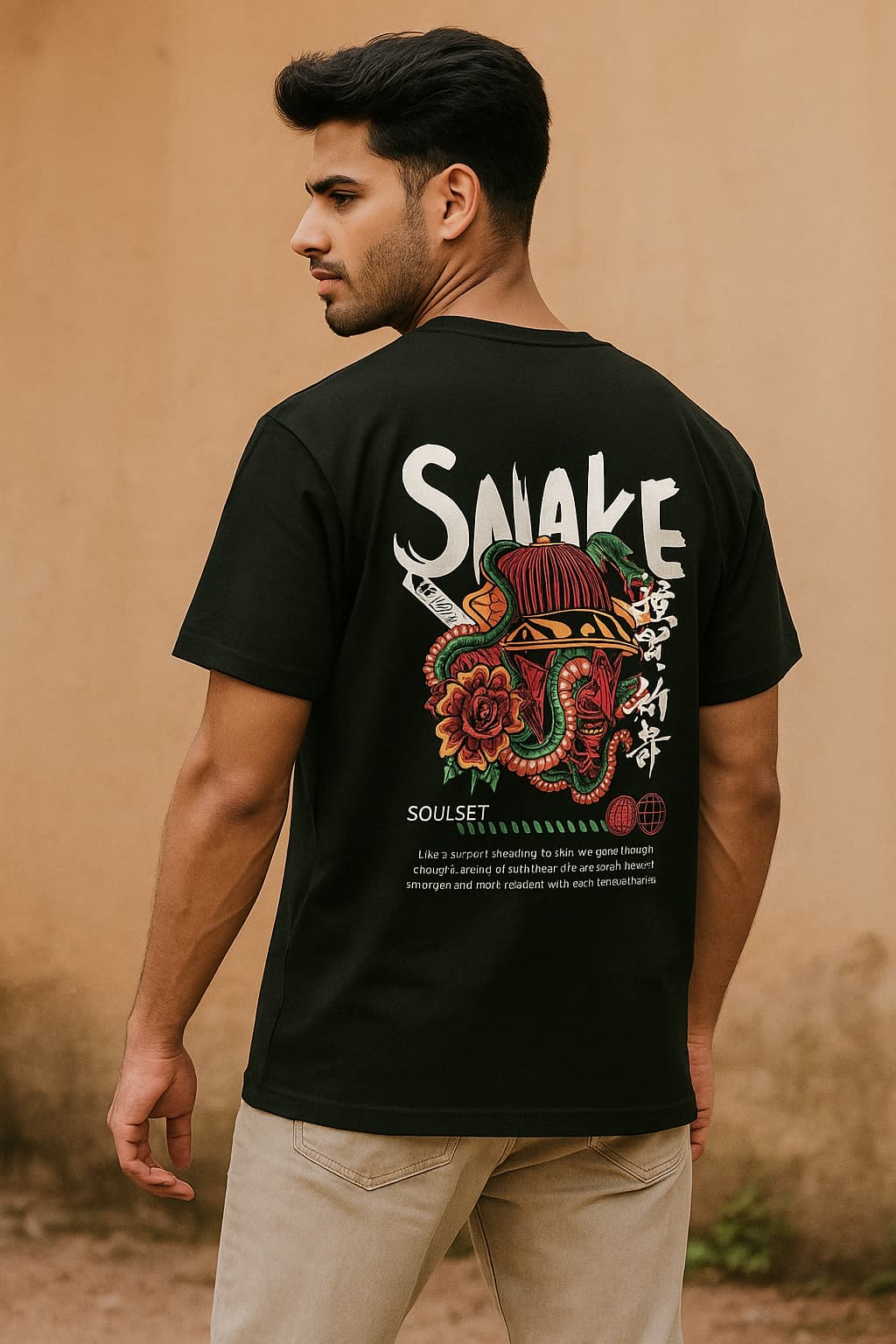 Man wearing a black t-shirt with a colorful graphic and text on the back, standing against a beige wall.