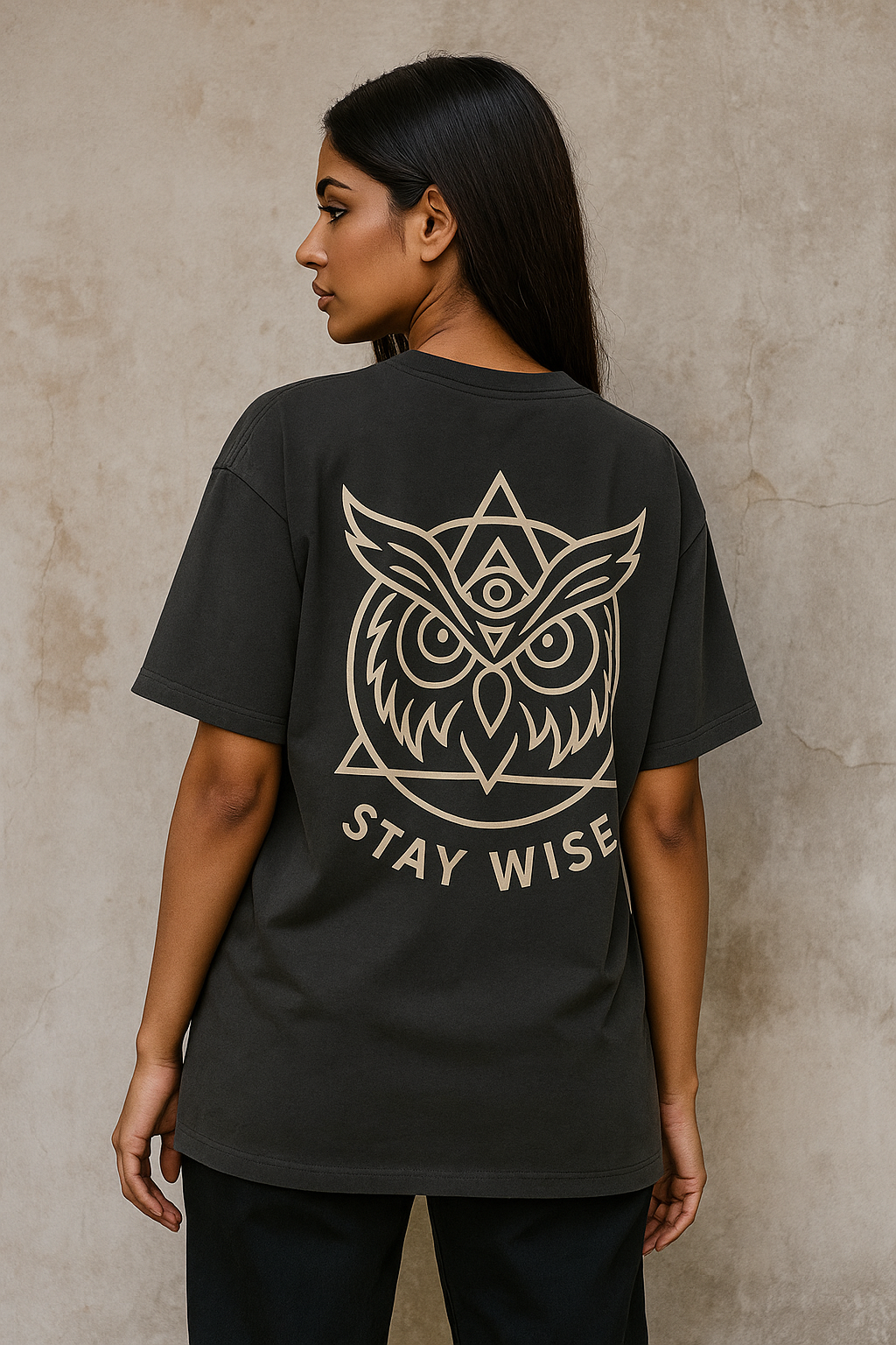 Oversized unisex t-shirt featuring a majestic owl with glowing eyes perched on a crescent moon, surrounded by sacred geometry and stardust detailing on the front. The back showcases an owl in flight fading into mist, with mandala feather rings and the phrase ‘Wisdom Sees All’ above.