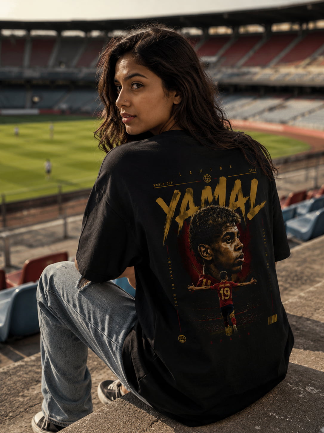 Person wearing a black t-shirt with a graphic design in an outdoor stadium setting