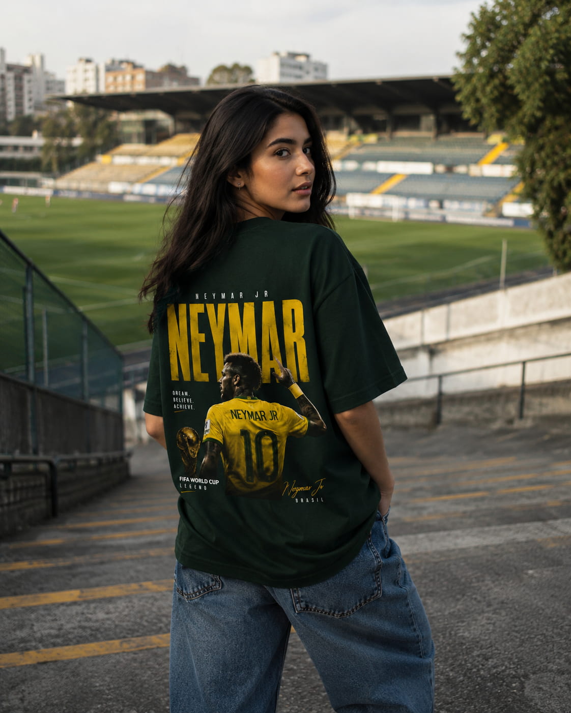 Person wearing a t-shirt with a graphic of Neymar Jr. at a stadium.