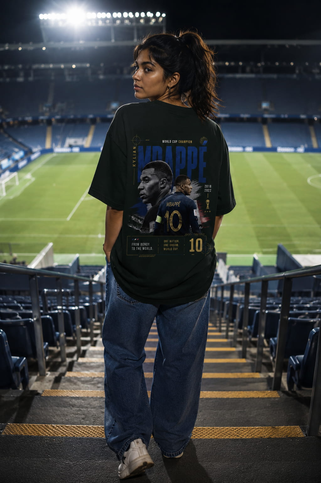 Person wearing a black t-shirt with a graphic design in an empty stadium