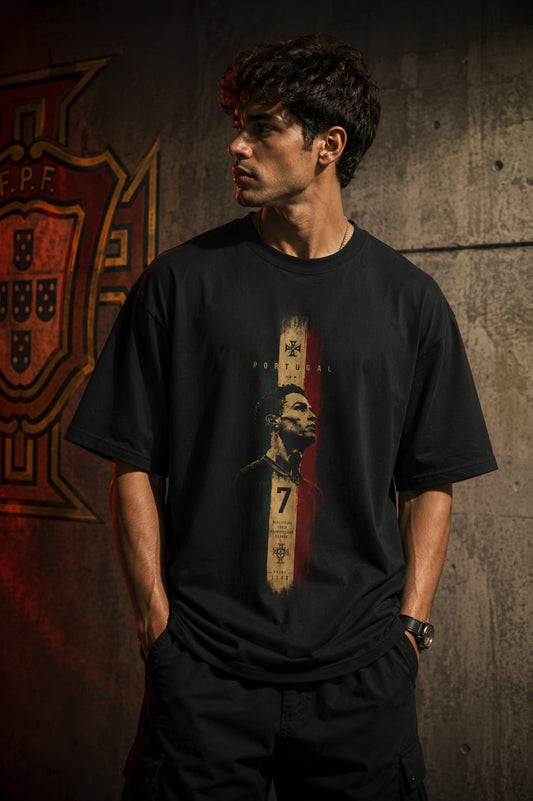 Person wearing a black t-shirt with a graphic design against a textured wall.