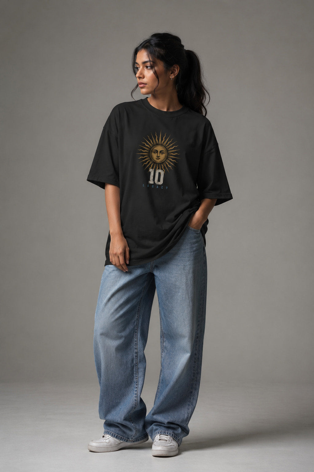 Woman wearing a black t-shirt with a design and blue jeans on a gray background