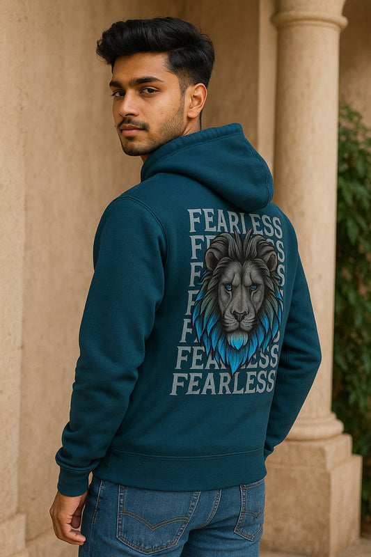 Man wearing a teal hoodie with a lion graphic and 'Fearless' text, standing in front of a beige architectural background.