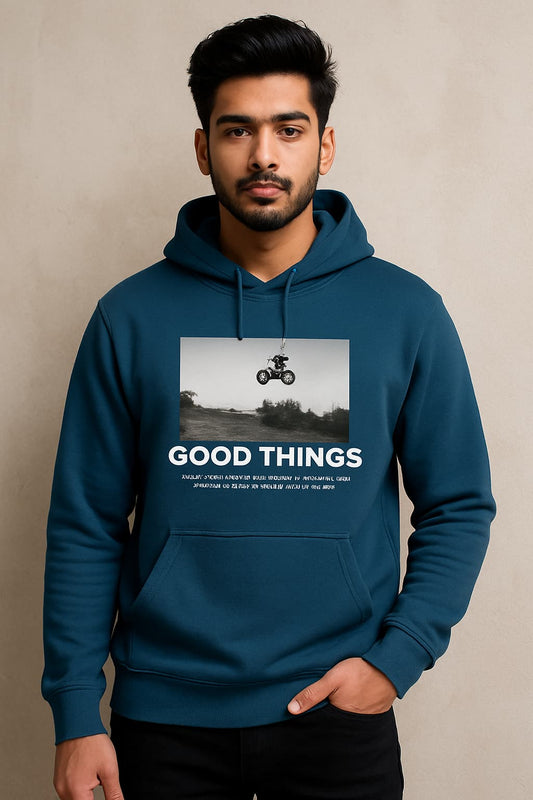 Man wearing a blue hoodie with 'GOOD THINGS' text and graphic on a beige background