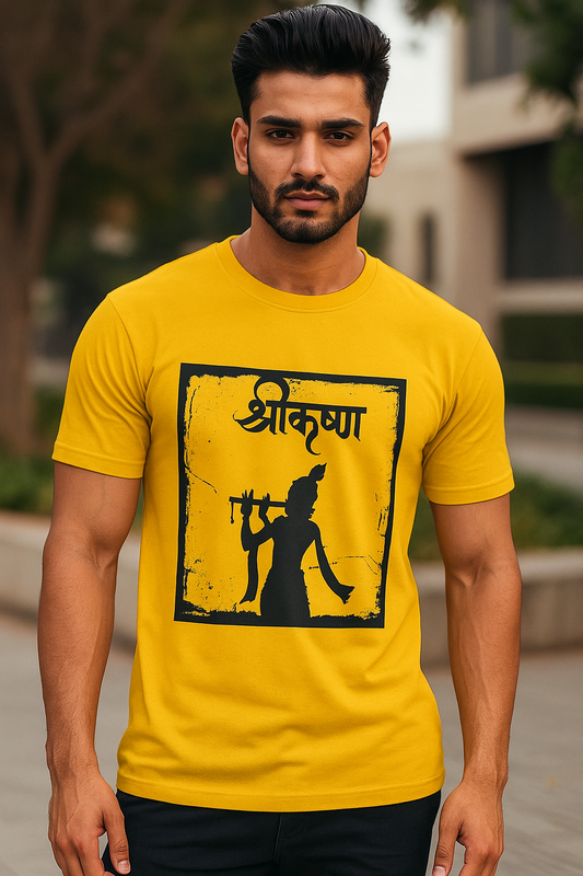 Confident young Indian man in his 20s wearing a yellow oversized T-shirt with a black Krishna silhouette graphic and Hindi text, posing outdoors in an urban background for an e-commerce fashion photoshoot.