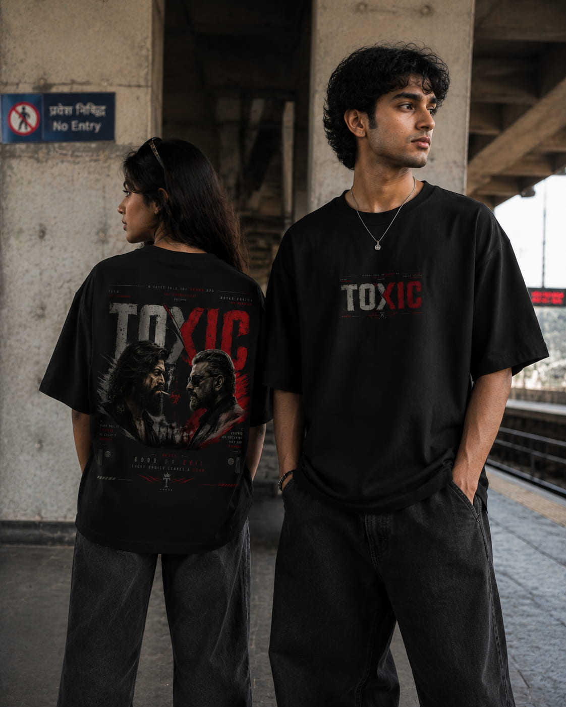 Two models wearing black graphic t-shirts in a train station setting. The model on the left shows the back of the shirt featuring a large red and white 'TOXIC' graphic with a horror illustration.