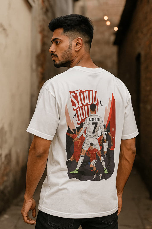 Man wearing a white t-shirt with a graphic design on the back, standing in an alleyway.