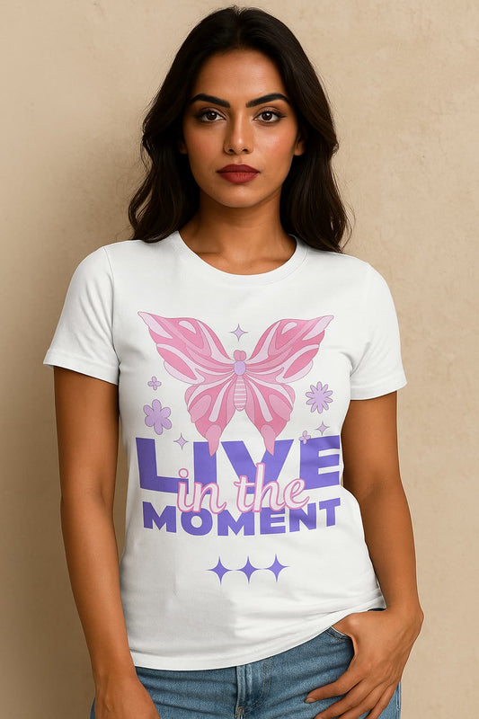 Woman wearing a white t-shirt with a pink butterfly graphic and 'Live in the Moment' text on a beige background